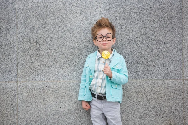 Bambino di moda con lecca-lecca vicino alla parete grigia — Foto Stock