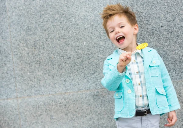 Bambino di moda con lecca-lecca vicino alla parete grigia — Foto Stock