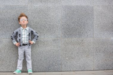 Gri duvarının yakınında gözlüklü moda çocuk
