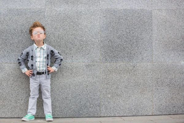 Enfant de mode avec des lunettes près du mur gris — Photo