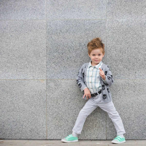 Fashion kid posing near gray wall — Stock Photo, Image