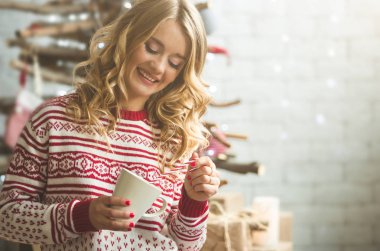 Genç güzel kadın kahve içme kış kar ağaç arka plan bulanık.