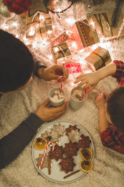 Vader en zoon onder de kerstboom te leggen. — Stockfoto