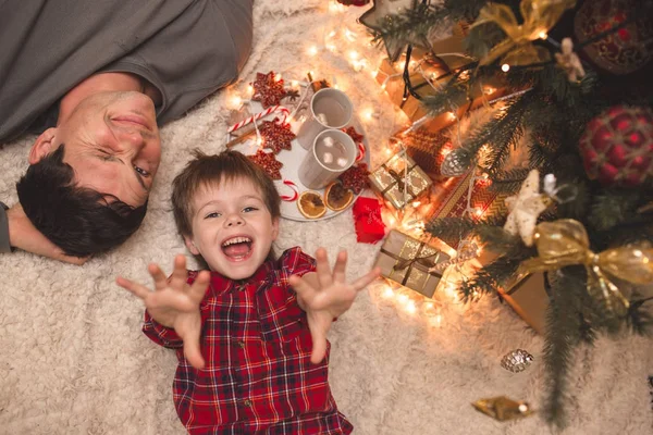 Père et fils couchés sous le sapin de Noël . — Photo