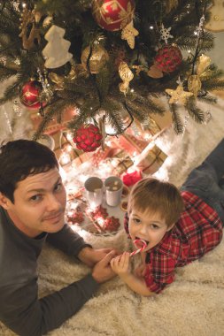 Baba ve oğul Noel ağacının altında döşeme.