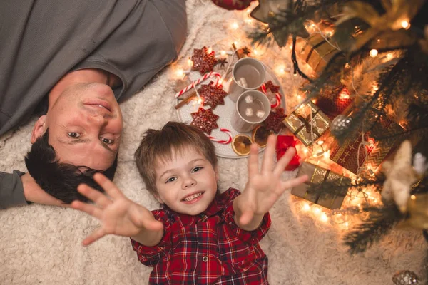 Отец и сын лежат под рождественской елкой . — стоковое фото