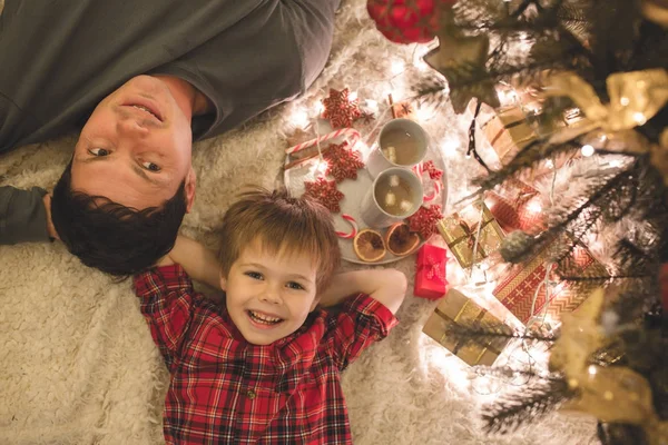 Père et fils couchés sous le sapin de Noël . — Photo