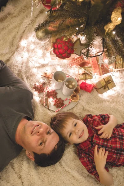 Père et fils couchés sous le sapin de Noël . — Photo