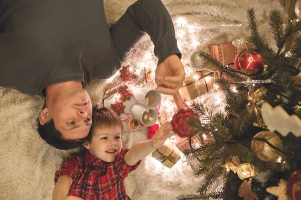 Père et fils couchés sous le sapin de Noël . — Photo