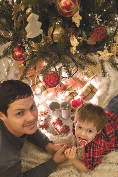 Père et fils couchés sous le sapin de Noël . — Photo