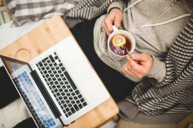 Genç adam Bad dizüstü bilgisayar ve çay döşeme.