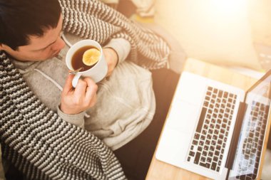 Genç adam Bad dizüstü bilgisayar ve çay döşeme.