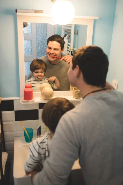 Молодой отец с сыном чистит зубы — стоковое фото
