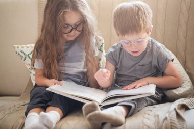 Küçük kardeşim ve kız kardeşi kanepede kitap okuma