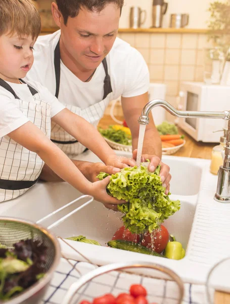 Homem e menino lavando legumes antes de comer — Fotografia de Stock
