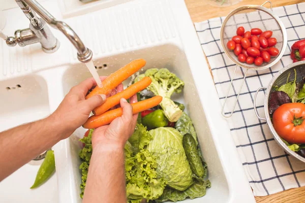 Man washing carrots before eating — Stock Photo, Image