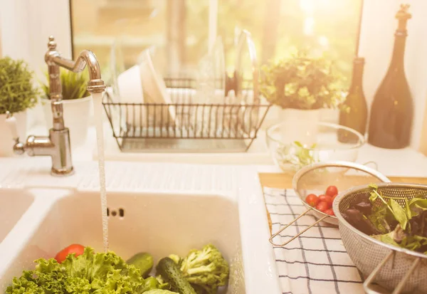 Vegetables lie in the sink near the window