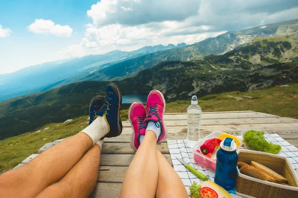 坐在高高的山上的木台上的旅行家的腿 自由概念 野餐在自然 Rila 山在保加利亚 — 图库照片