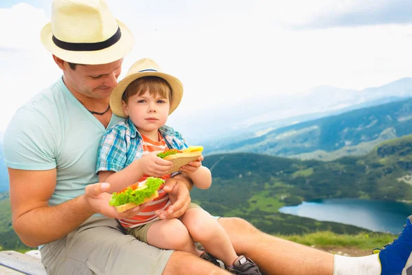 父と息子は 山でのピクニックの健全なサンドイッチを食べる ブルガリアのリラ湖 — ストック写真