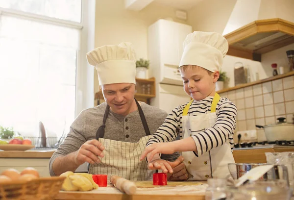 Pai e filho em chapéus de chef estão cozinhando — Fotografia de Stock