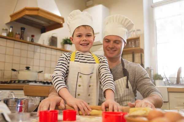 Pai e filho em chapéus de chef estão cozinhando — Fotografia de Stock