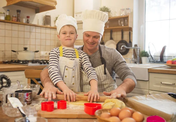 Pai e filho em chapéus de chef estão cozinhando — Fotografia de Stock