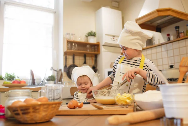 Two little brothers in chef's hats are cooking — Stock Photo, Image