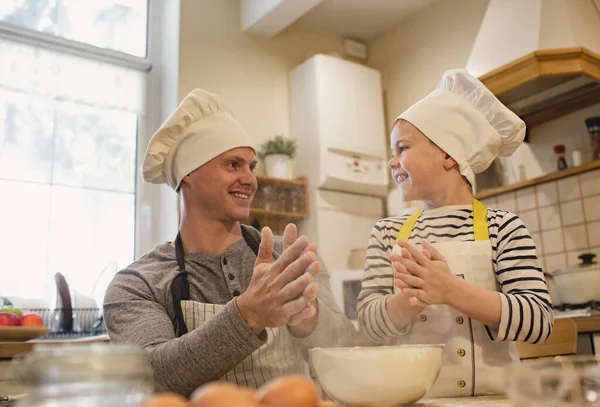 Pai e filho em chapéus de chef estão cozinhando — Fotografia de Stock