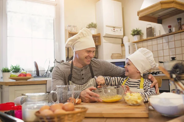 Папа и сын в шляпах шеф-повара готовят — стоковое фото