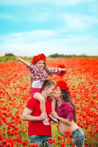 Pregnant woman her husband and their daughter in poppy field — ストック写真