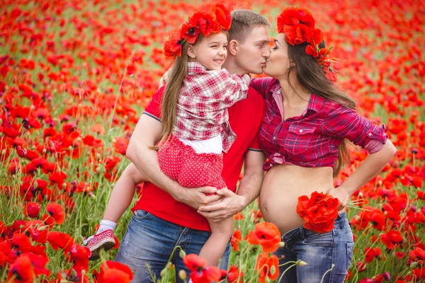 Pregnant woman her husband and their daughter in poppy field — Stok fotoğraf