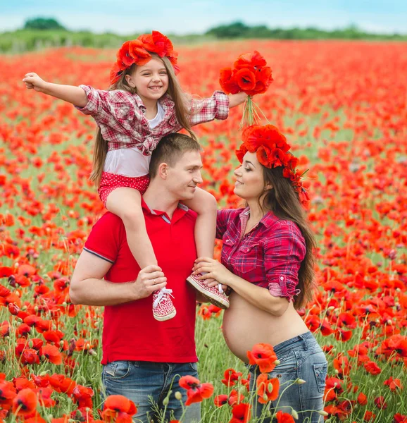 Těhotná žena její manžel a jejich dcera v máku pole — Stock fotografie