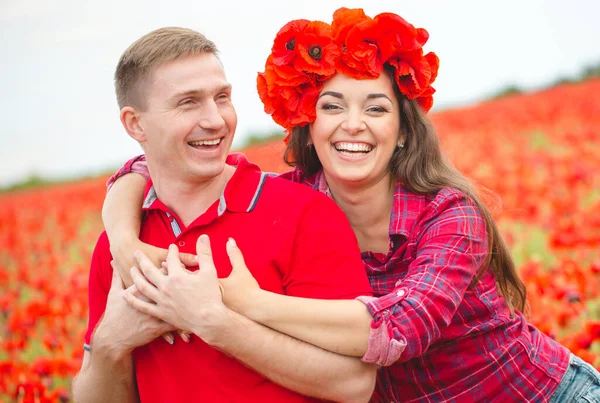 Young couple of lovers in a poppy field — Stock Photo, Image