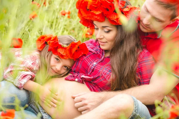 Pregnant woman her husband and their daughter in poppy field — Stok fotoğraf