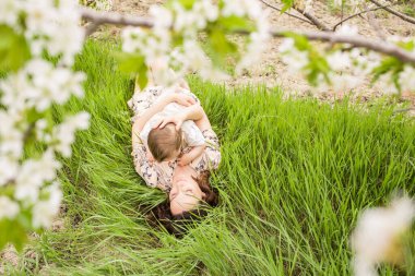 Güzel genç anne oğluyla bahar bahçesinde oynuyor. Köyde tatil.