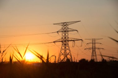 Gün batımında yüksek voltajlı güç hattı silueti