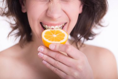 Closeup young woman face with lemon fruit. Wearing teeth braces