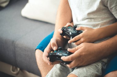 man playing video game console with son at home