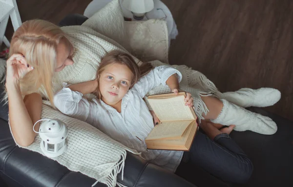 The family in the period of self-isolation reads books at home on the couch. How to keep yourself busy during quarantine without leaving your home