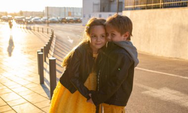 Little kids walk together. Stylishly dressed fashionable kids. A teenager in yellow jeans, and a girl in a yellow dress.