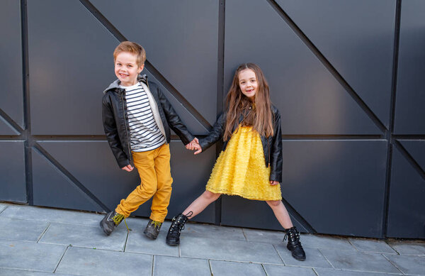 Маленькие дети ходят вместе. Стильно одетые модные детишки. Подросток в жёлтых джинсах и девушка в жёлтом платье
.
