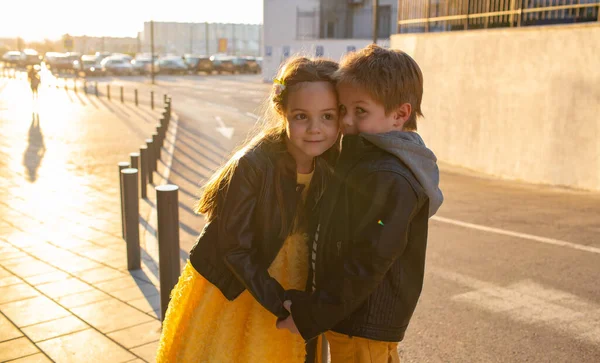 Little kids walk together. Stylishly dressed fashionable kids. A teenager in yellow jeans, and a girl in a yellow dress.