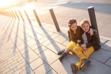 Little kids walk together. Stylishly dressed fashionable kids. A teenager in yellow jeans, and a girl in a yellow dress.