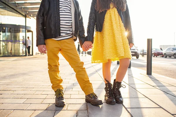 Little kids walk together. Stylishly dressed fashionable kids. A teenager in yellow jeans, and a girl in a yellow dress.