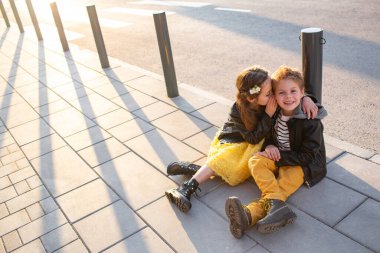 Little kids walk together. Stylishly dressed fashionable kids. A teenager in yellow jeans, and a girl in a yellow dress.