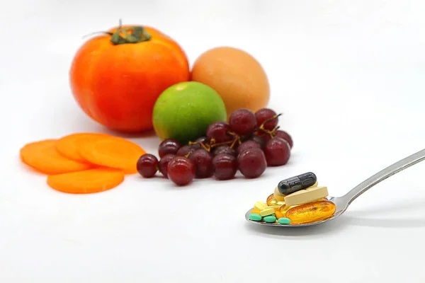 Válogatott vitaminok és táplálék-kiegészítóket szedőkanállal. blur színes gyümölcsök háttér Stock Fotó