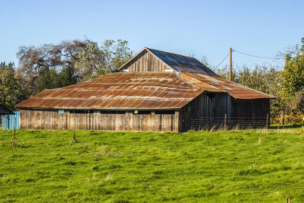 Staré, šikmá dřevěná stodola s zrezivělé plechové střechy — Stock fotografie