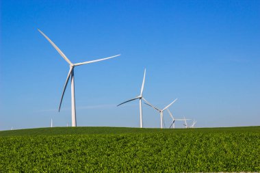 Enerji üreten üç kanatlı yel değirmenleri ile yeşil alan