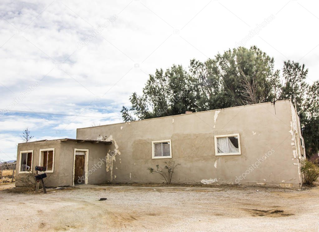 Abandoned One Story Adobe Home With Boarded Up Windows