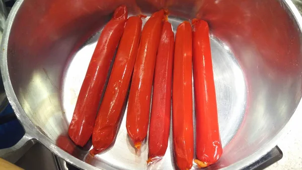 Червоні ковбаски на сковороді — стокове фото